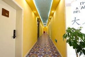 A hotel hallway with a patterned carpet, a plant on the right, and a sign with Japanese characters. - Wuwangwo Hotel (Burqin)