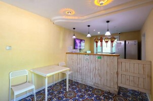 Una habitación con mostrador de madera, dos sillas blancas, una mesa y piso con diseño.