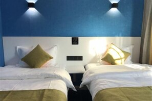 A hotel room with two beds, each with a pillow and a headboard. There are wall-mounted light fixtures above the beds. - Wuwangwo Hotel (Burqin)