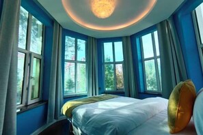 A bedroom with a large bed, multiple windows, and a ceiling light fixture. - Wuwangwo Hotel (Burqin)