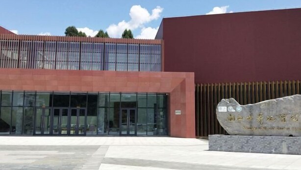 A modern building with a glass facade and a stone plaque in front. - Yongshun Pinghe Homestay (Yongshun)