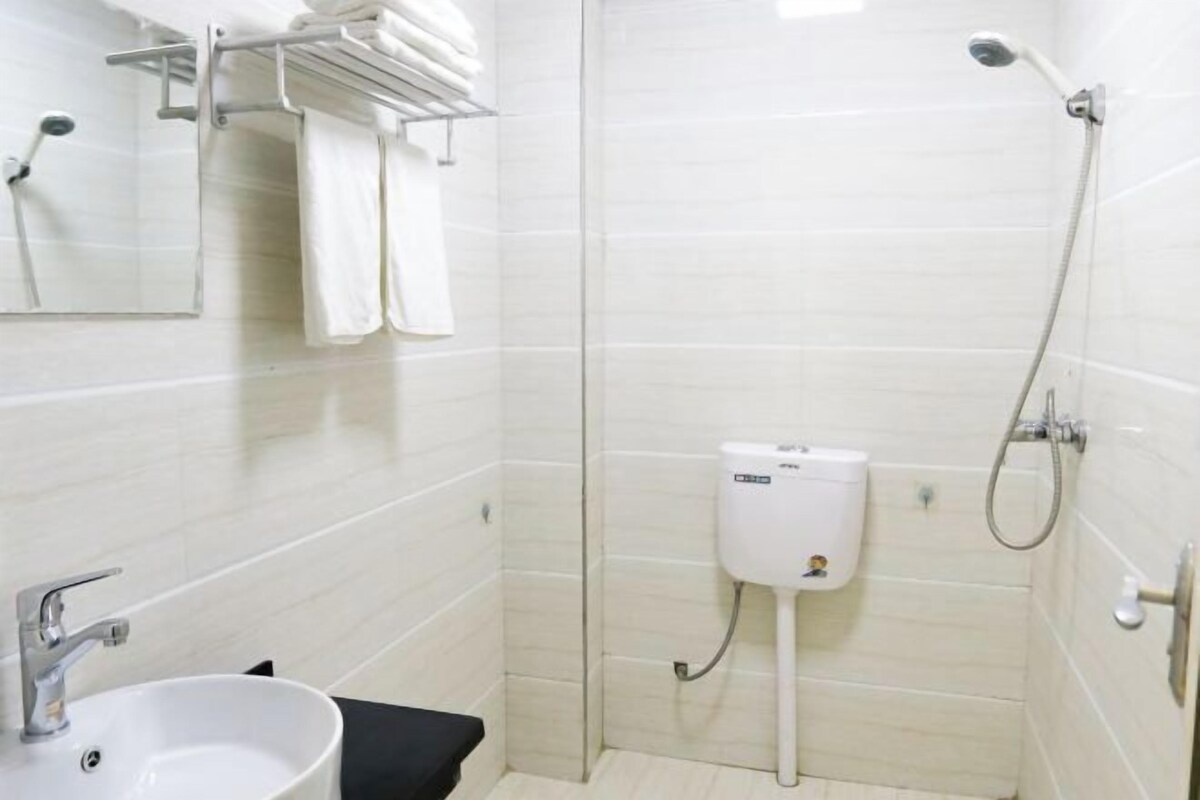 A bathroom with a sink, mirror, towel rack, toilet, and shower.