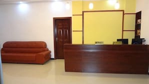A reception area with a wooden desk, a sofa, and a door. - Yongshun Pinghe Homestay (Yongshun)