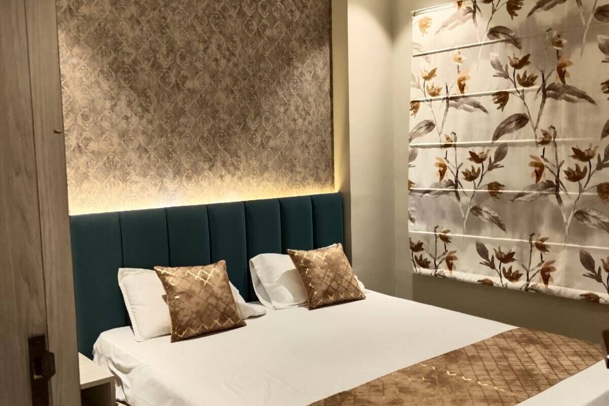 A modern hotel room with a large bed, a headboard with a patterned wallpaper, an air conditioning unit, and a floral curtain.