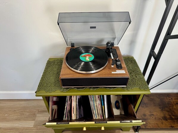 A turntable on a green table with a record collection underneath.