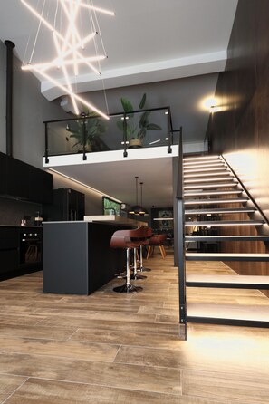 A modern kitchen with a central island, a staircase, and a dining area with chairs. - 180M2-Luxurious-Renovated Holiday LOFT, best rental in Olbia (Olbia)
