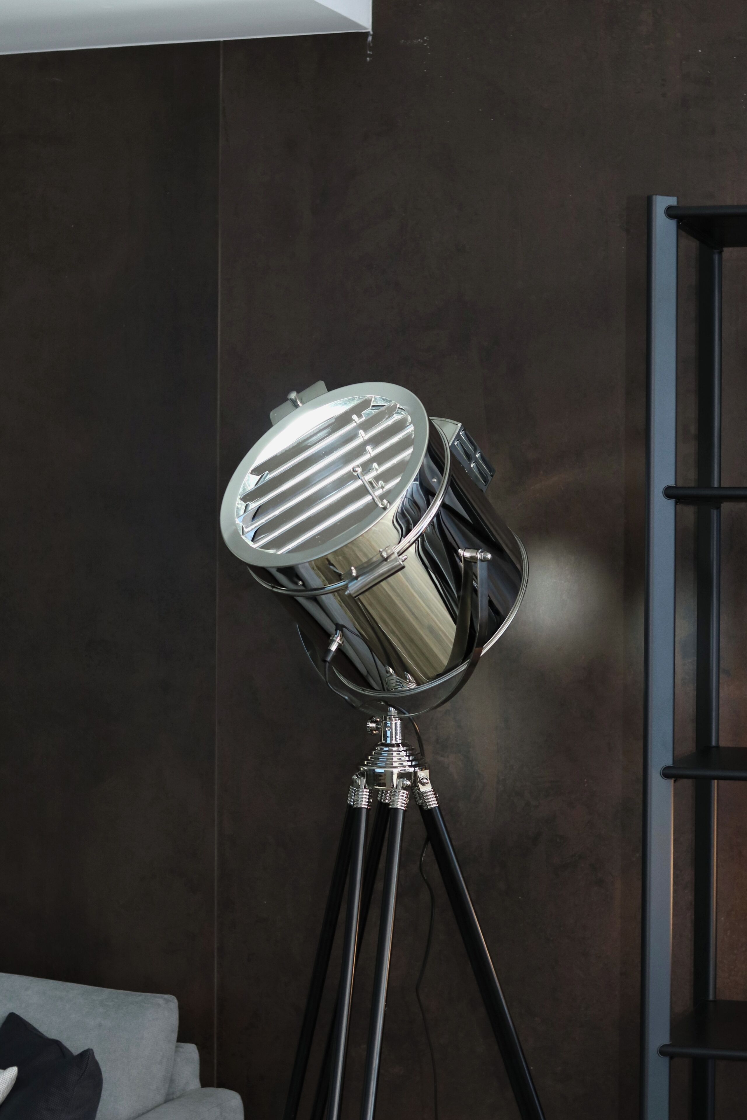 A modern room with a large, metallic, circular light fixture on a tripod stand.
