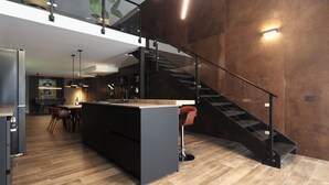 A modern kitchen with a central island, a dining area with chairs, a staircase, and a view of the living area. - 180M2-Luxurious-Renovated Holiday LOFT, best rental in Olbia (Olbia)