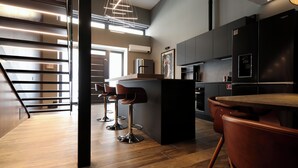 A modern kitchen with a central island, bar stools, and a wooden dining table. - 180M2-Luxurious-Renovated Holiday LOFT, best rental in Olbia (Olbia)