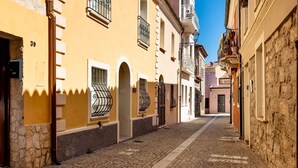 A narrow cobblestone street flanked by buildings with stone facades and arched doorways. - Olbia Old Town Townhouse: 2BR Renovated, Parking, Steps to Harbor & Beaches (Olbia)
