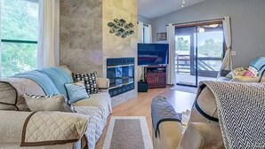 Un salon doté d’une cheminée, d’un ventilateur de plafond et d’une grande fenêtre.
