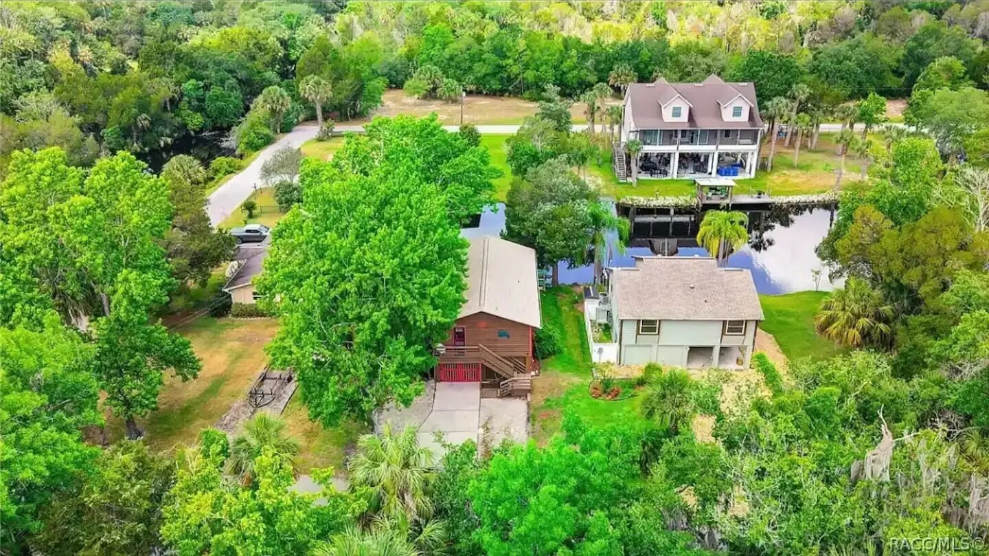 A large house with a two-story structure, surrounded by lush greenery and a small pond.