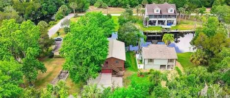 A large house with a two-story structure, surrounded by lush greenery and a small pond.