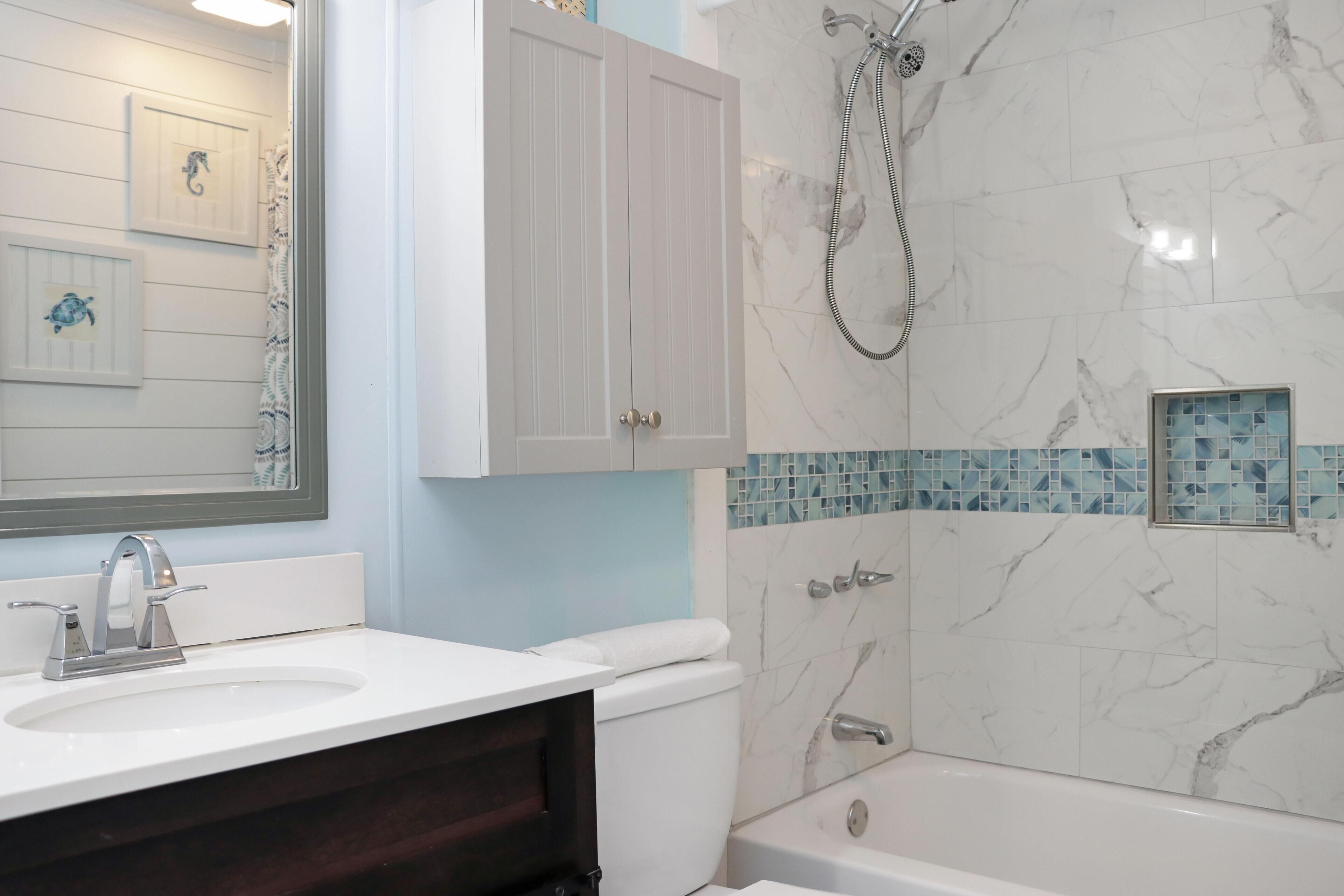 Une salle de bain avec un lavabo blanc, des toilettes, une baignoire et une douche.