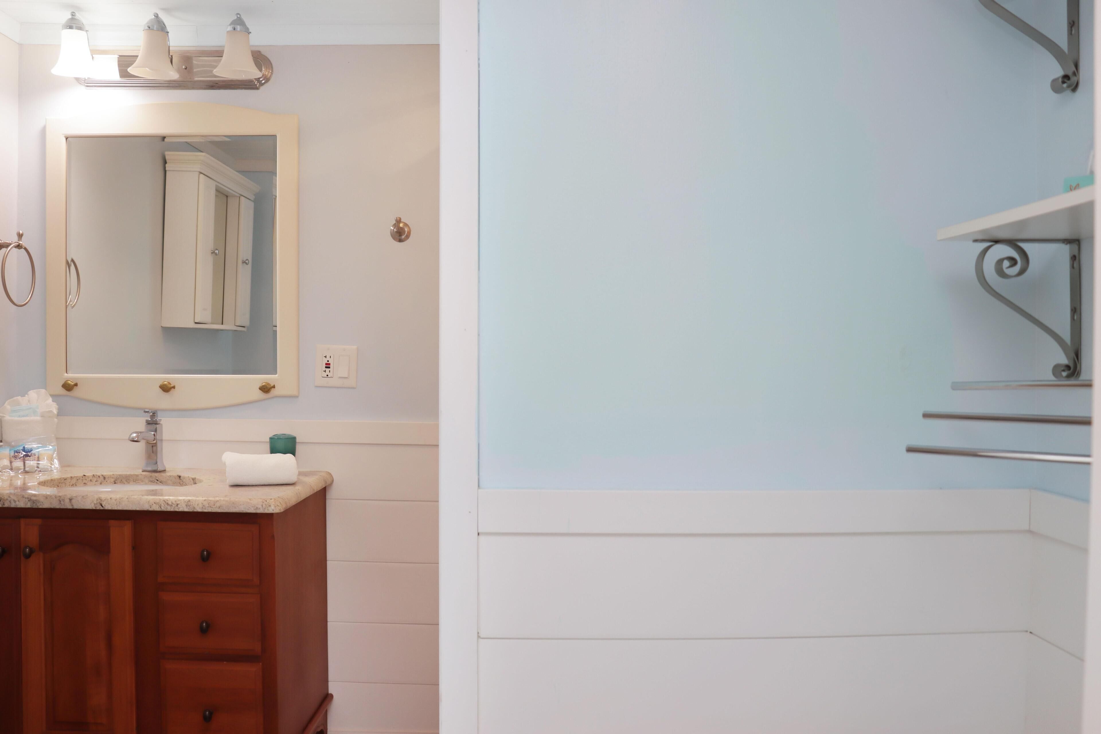 A bathroom with a wooden vanity, a mirror, and a white sink.