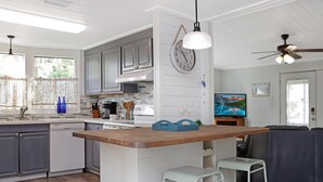 Een moderne keuken met witte kasten, een houten kookeiland en barstoelen.