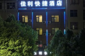Een hotel met een bord in Chinese karakters, meerdere ramen en airconditioningsinstallaties.