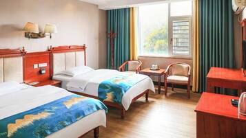 A hotel room with two beds, a desk, a chair, and a window with curtains.