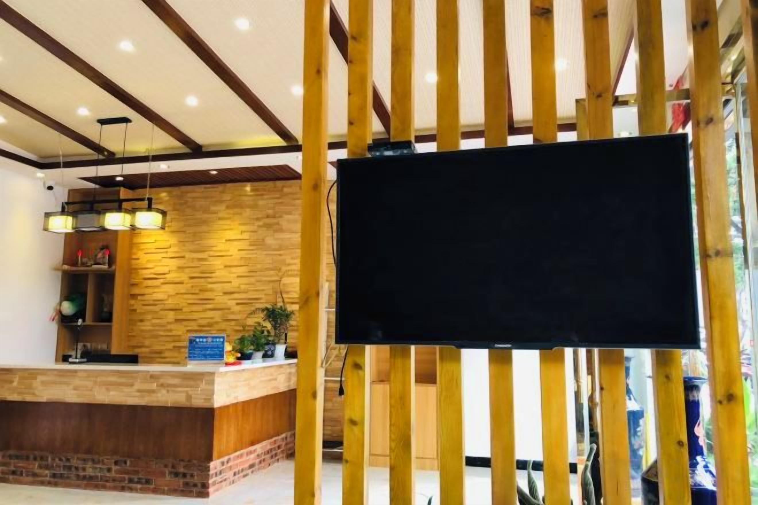 A reception area with a wooden reception desk, a flat-screen TV, and a brick accent wall.