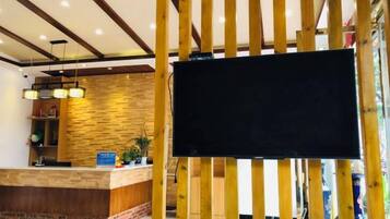 A reception area with a wooden reception desk, a flat-screen TV, and a brick accent wall.