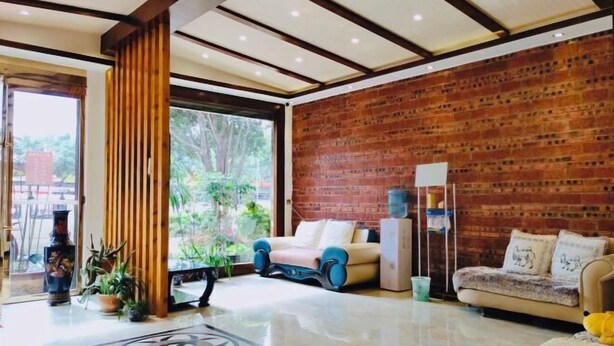 Un interior moderno con pared de ladrillo, dos sofás, una mesa de centro y un ventanal grande.