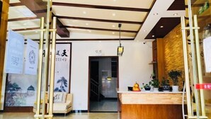 Un área de recepción con un mostrador de madera, una lámpara colgante y una pared decorada con obras enmarcadas.