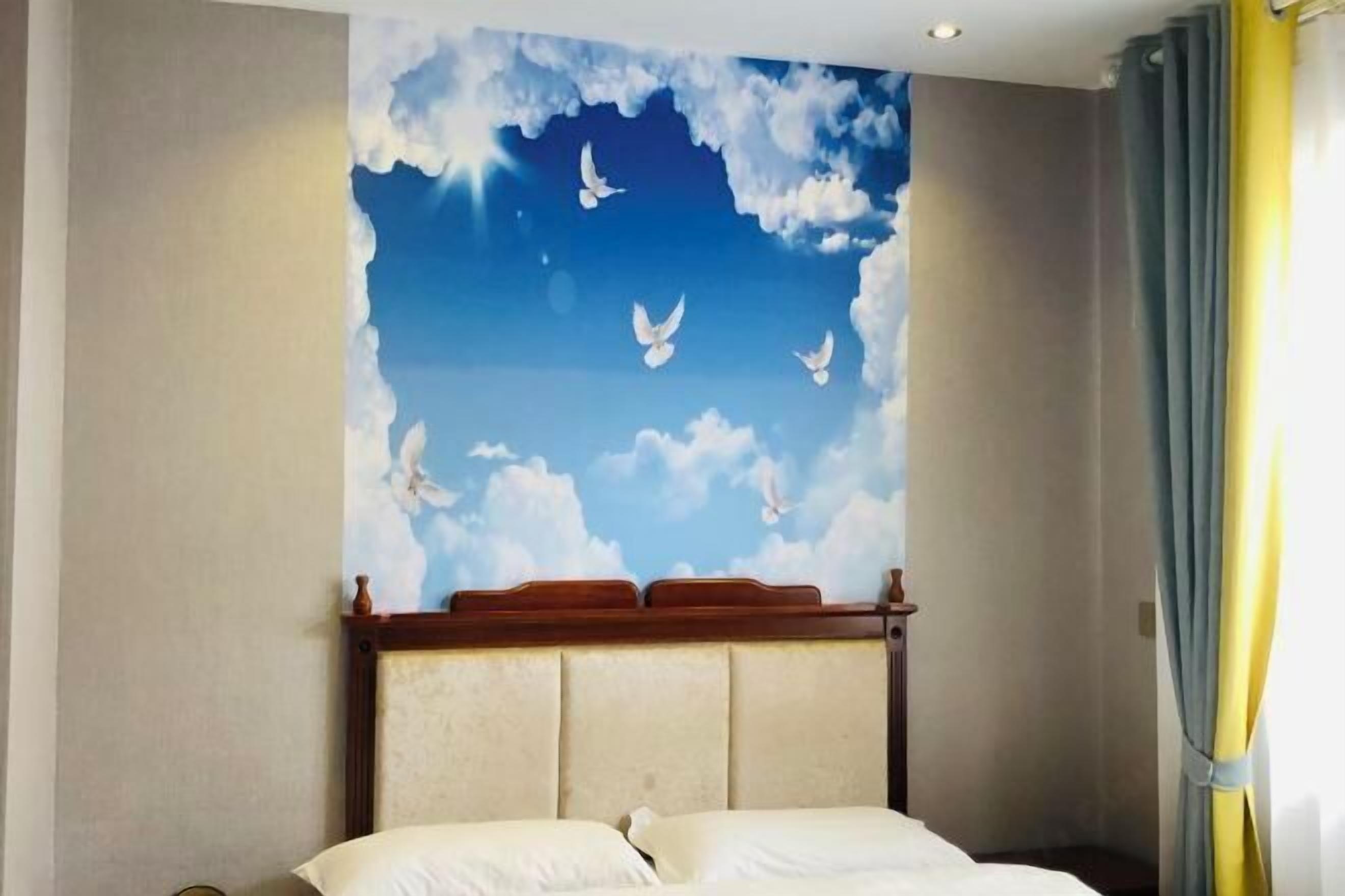 Une chambre à coucher avec un lit, une tête de lit et une fresque murale représentant des nuages et des oiseaux.