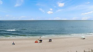 Een strand met een heldere lucht, rustige zee en verschillende strandparasols.