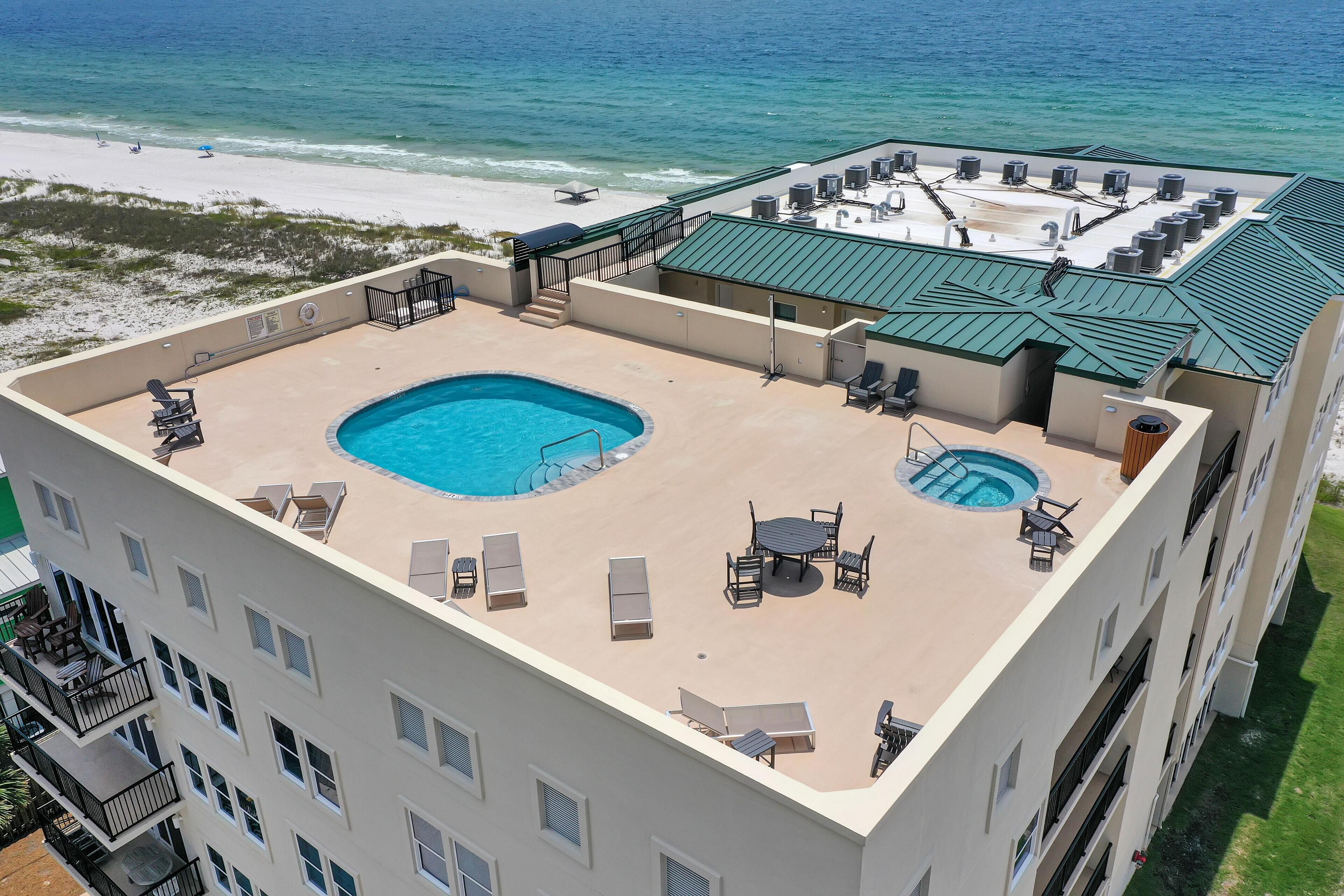 A rooftop pool area with a view of the beach and ocean.