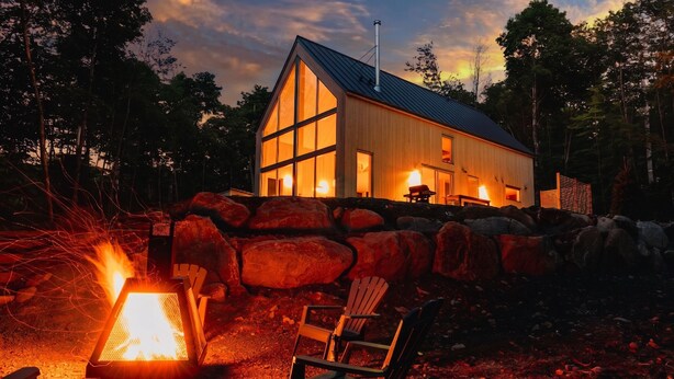 Et moderne hus med en stenvæg, en pejseplads og to stole.