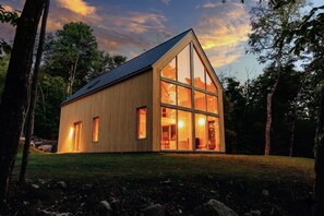 A modern wooden cabin with large windows, set in a forested area. - Mont-Tremblant North side | Scandinavian Chalet with Spa (Les Laurentides)