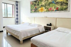 Une chambre d’hôtel avec deux lits, un grand tableau floral accroché au mur, une fenêtre avec des rideaux et une table de chevet avec un téléphone.