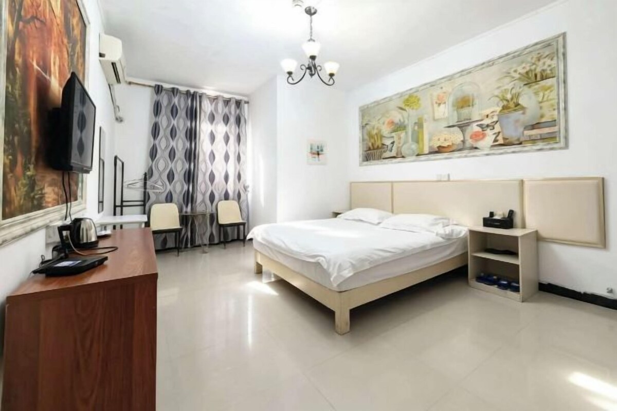 Een hotelkamer met een bed, een bureau, een stoel, een televisie en een schilderij aan de muur.