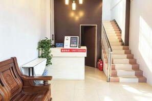 Un espace d’accueil comprenant un comptoir de réception, un escalier et un banc en bois.