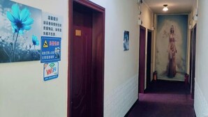 A hallway with a purple carpet, a door on the left, and a painting on the right. - An Inn (Guilin Yiyuan Branch) (Guilin)