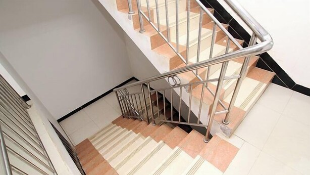 A staircase with a metal railing and beige and white tiles. - An Inn (Guilin Yiyuan Branch) (Guilin)