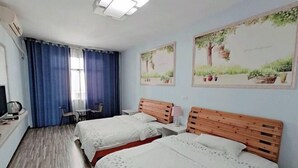 A hotel room with two beds, a desk with a chair, a small table, and a window with blue curtains. - An Inn (Guilin Yiyuan Branch) (Guilin)