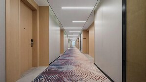 A long, narrow hallway with wooden walls and a patterned carpet. - haofeng S hotel (Chengdu)