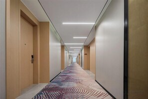 Ein Hotelkorridor mit Teppichmuster, Holztüren und einer langen Diele.