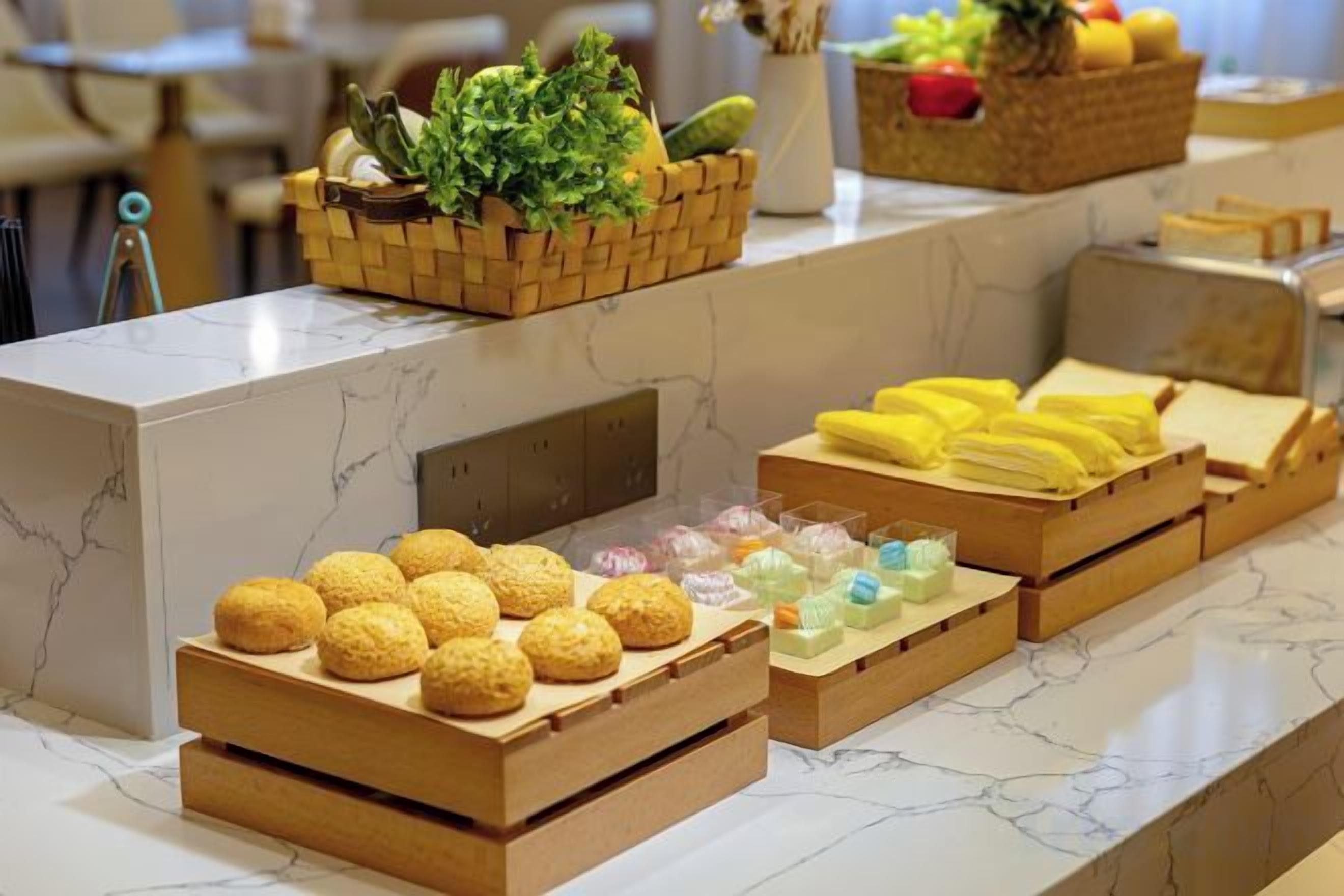 A buffet with various food items and fresh produce displayed on a marble countertop.