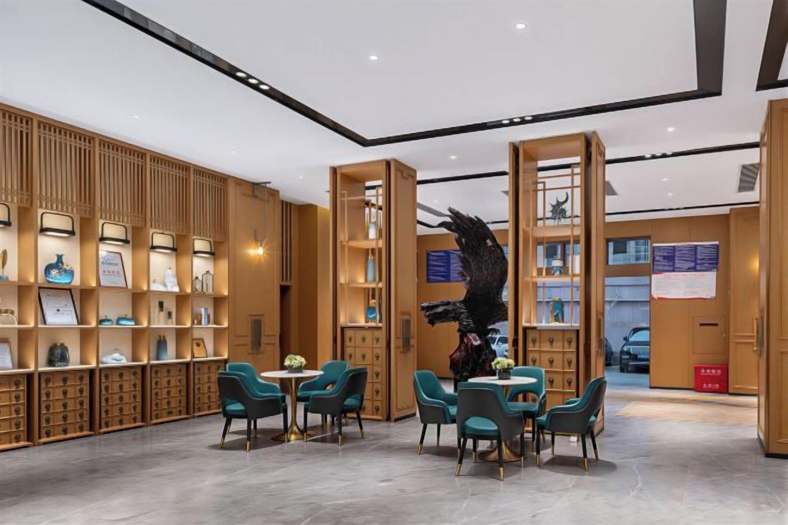 A hotel lobby with a central seating area, wooden shelving with framed items, and a large black sculpture.