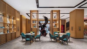A modern interior with wooden shelving, teal chairs, and a central sculpture. - haofeng S hotel (Chengdu)