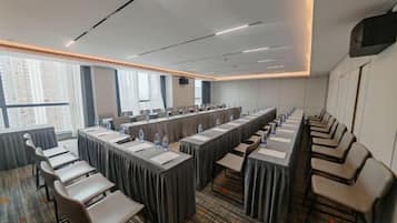 A conference room with long tables, chairs, and a projector screen.