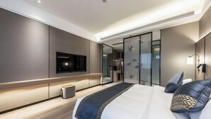 A modern hotel room with a large bed, a flat-screen TV, a mirror, and a small trash bin. - haofeng S hotel (Chengdu)