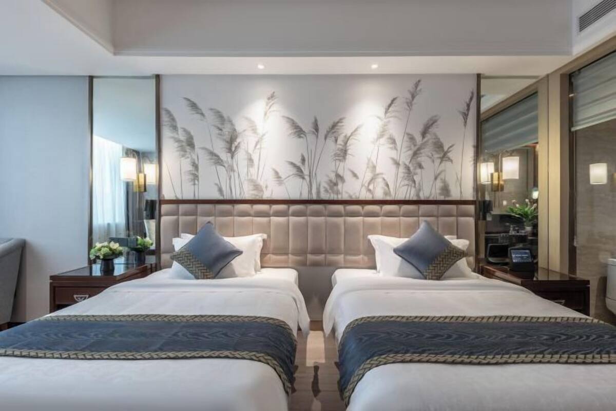 Quarto de hotel com duas camas, uma obra de arte grande pendurada na parede e uma cabeceira moderna.