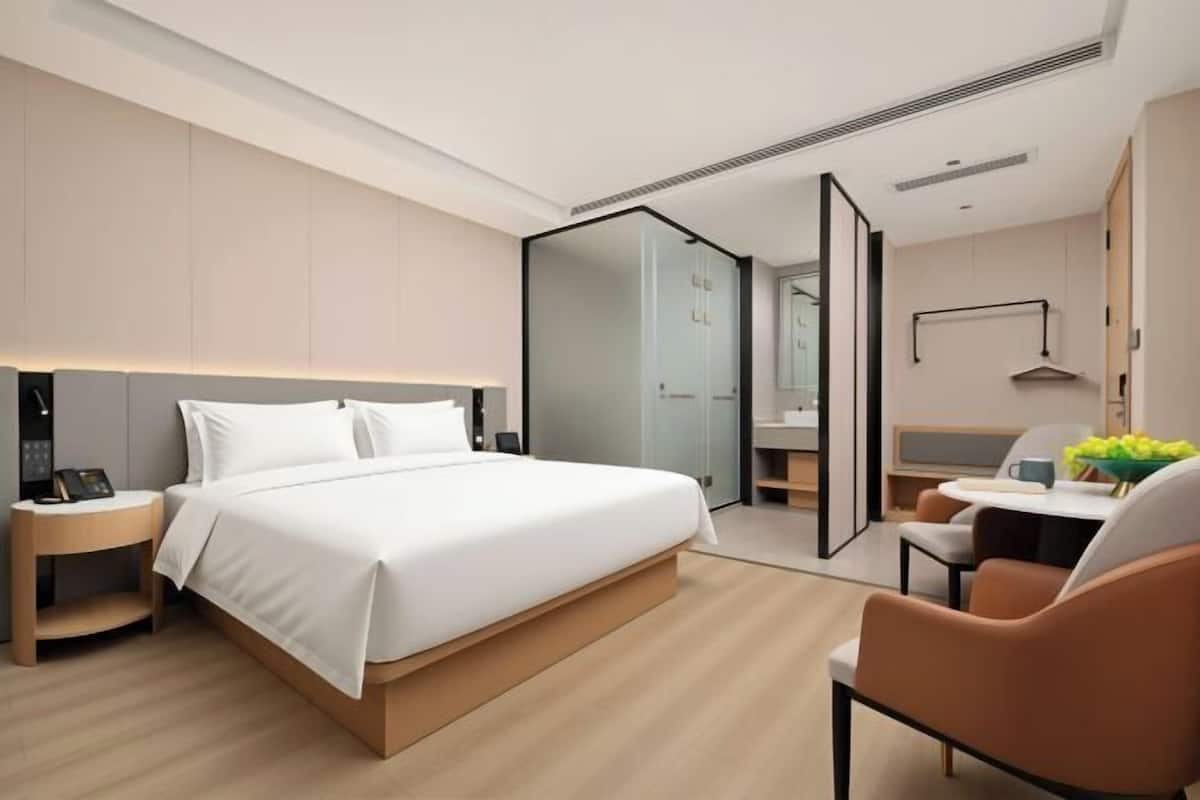 Quarto de hotel moderno com uma cama grande, mesa de cabeceira e escrivaninha com uma cadeira.