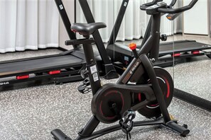 A stationary exercise bike with a digital display, positioned in a room with a carpeted floor and a window with curtains. - haofeng S hotel (Chengdu)