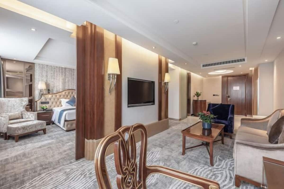 Quarto de hotel moderno com cama, área de estar e televisão.