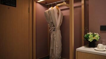A wooden-framed walk-in closet with a robe hanging on a rack, a small table with a vase of flowers, and a wall-mounted sign.
