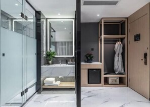 Un baño moderno con mampara de vidrio, lavamanos, espejo, toallero y mueble de madera.